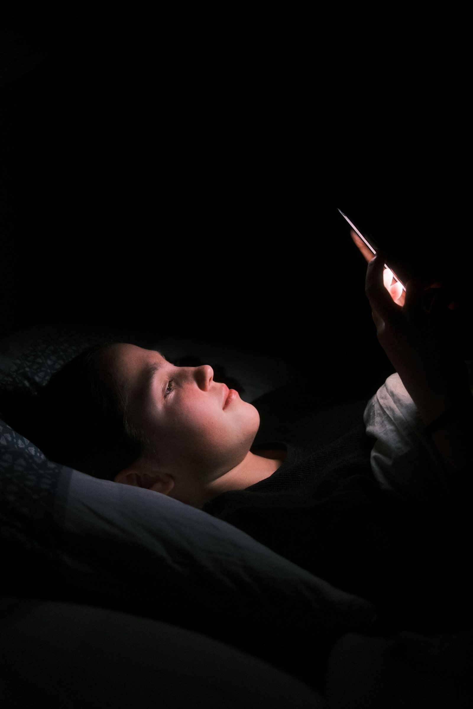 Person using smartphone in bed, affecting deep sleep